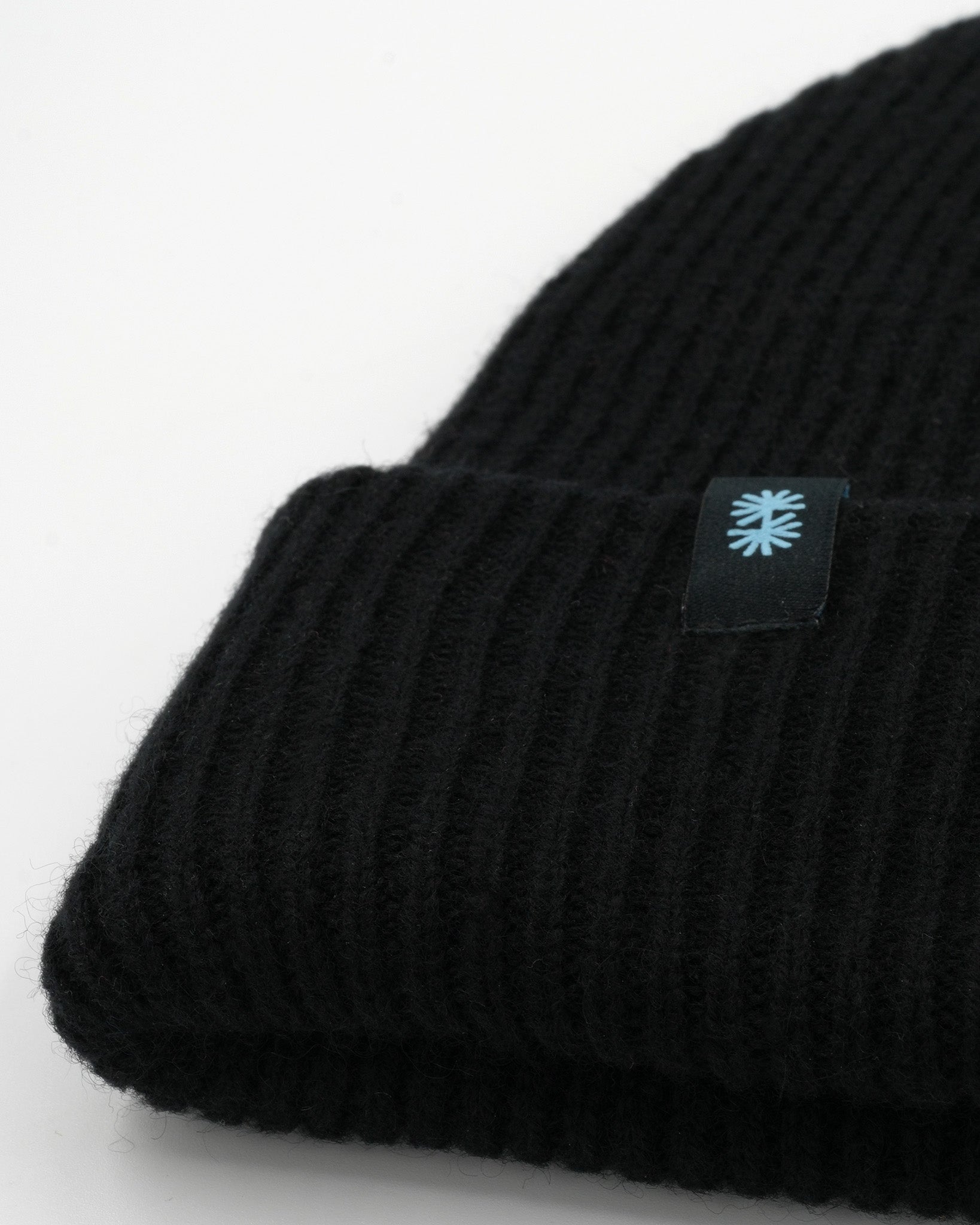 Black cashmere merino wool beanie with black woven label close-up