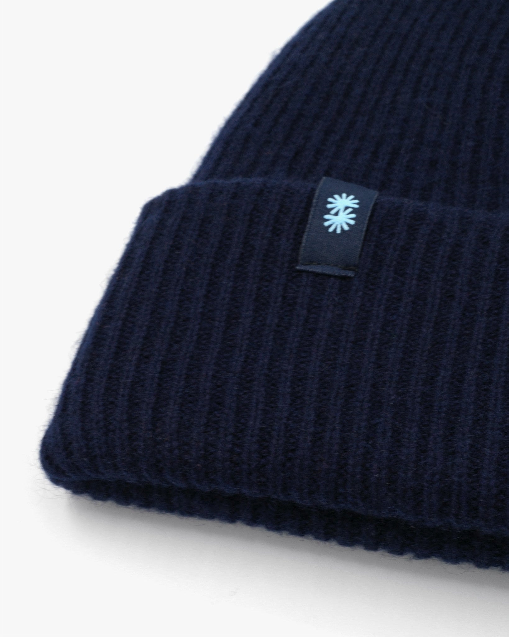 Dark blue cashmere merino wool beanie with yellow woven label close-up