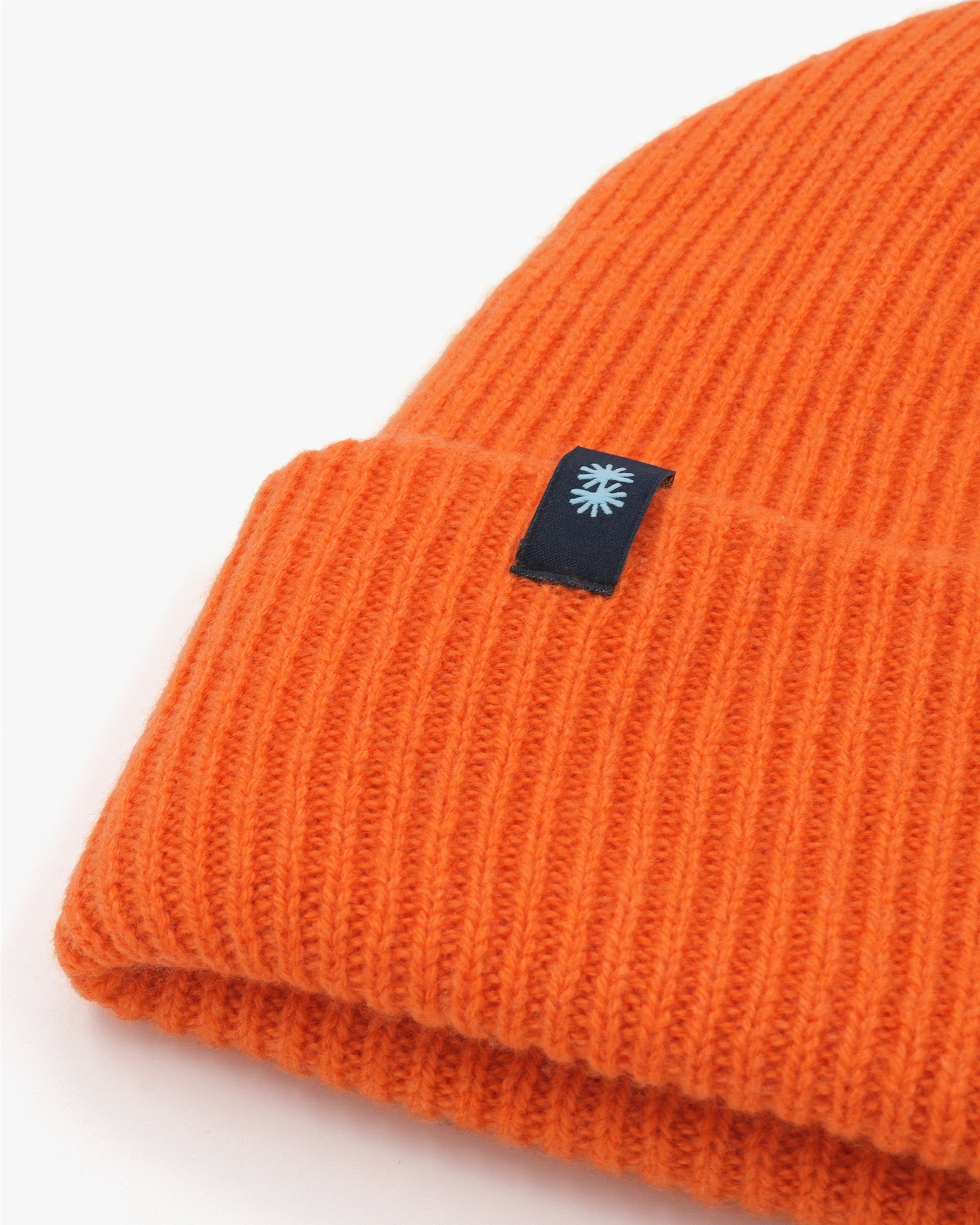 Orange cashmere merino wool beanie with black woven label close-up