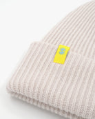 Off-white cashmere merino wool beanie with yellow woven label close-up