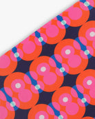 Close-up of a goggle cover with a bright pink and red circles on dark blue background geometric print