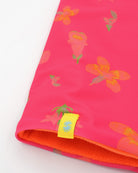 Close-up view of a double layer neck warmer with a hot pink floral printed lycra, orange fleece lining and yellow CTW logo woven label