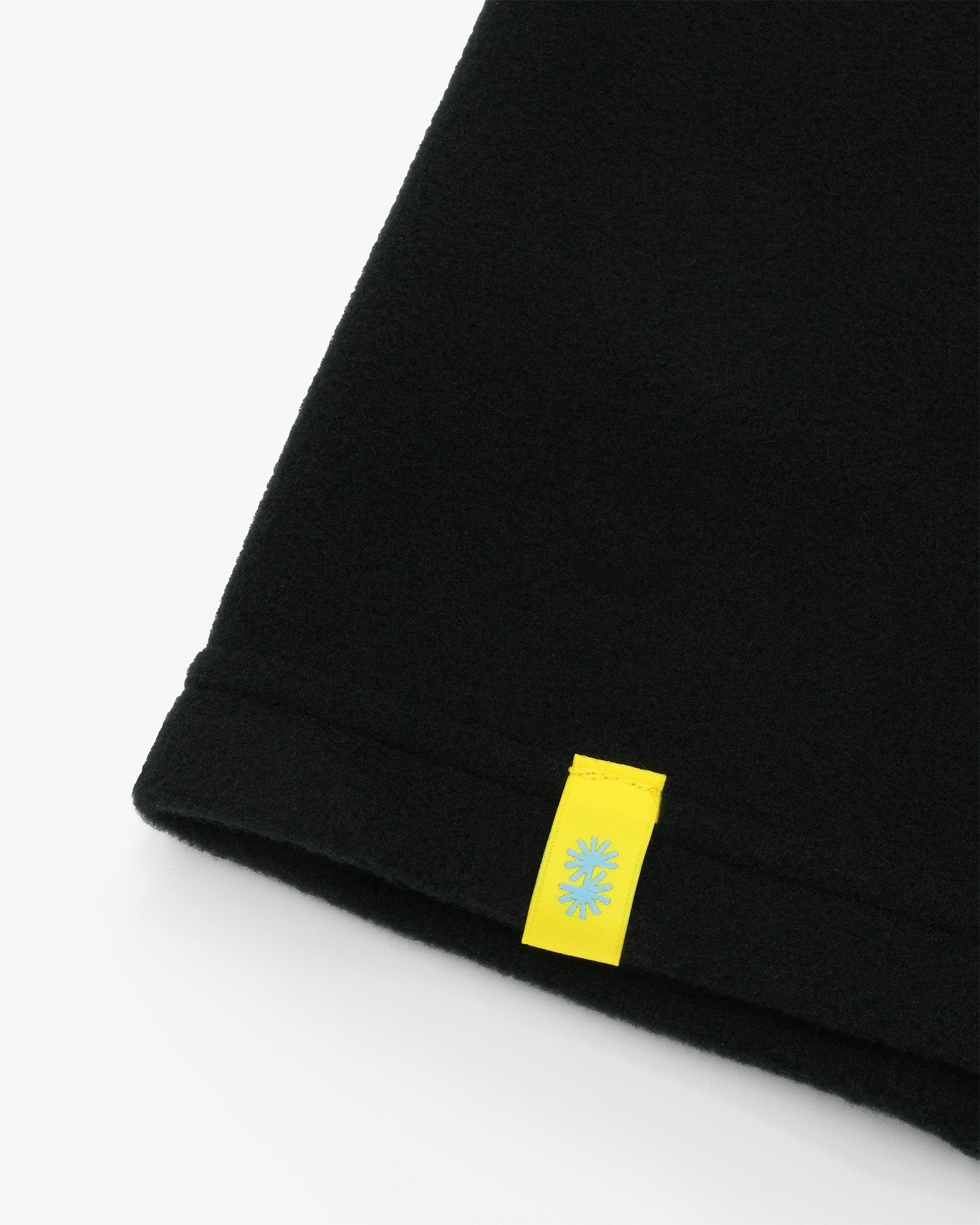 Black polartec fleece short neck warmer with yellow CTW woven logo close-up