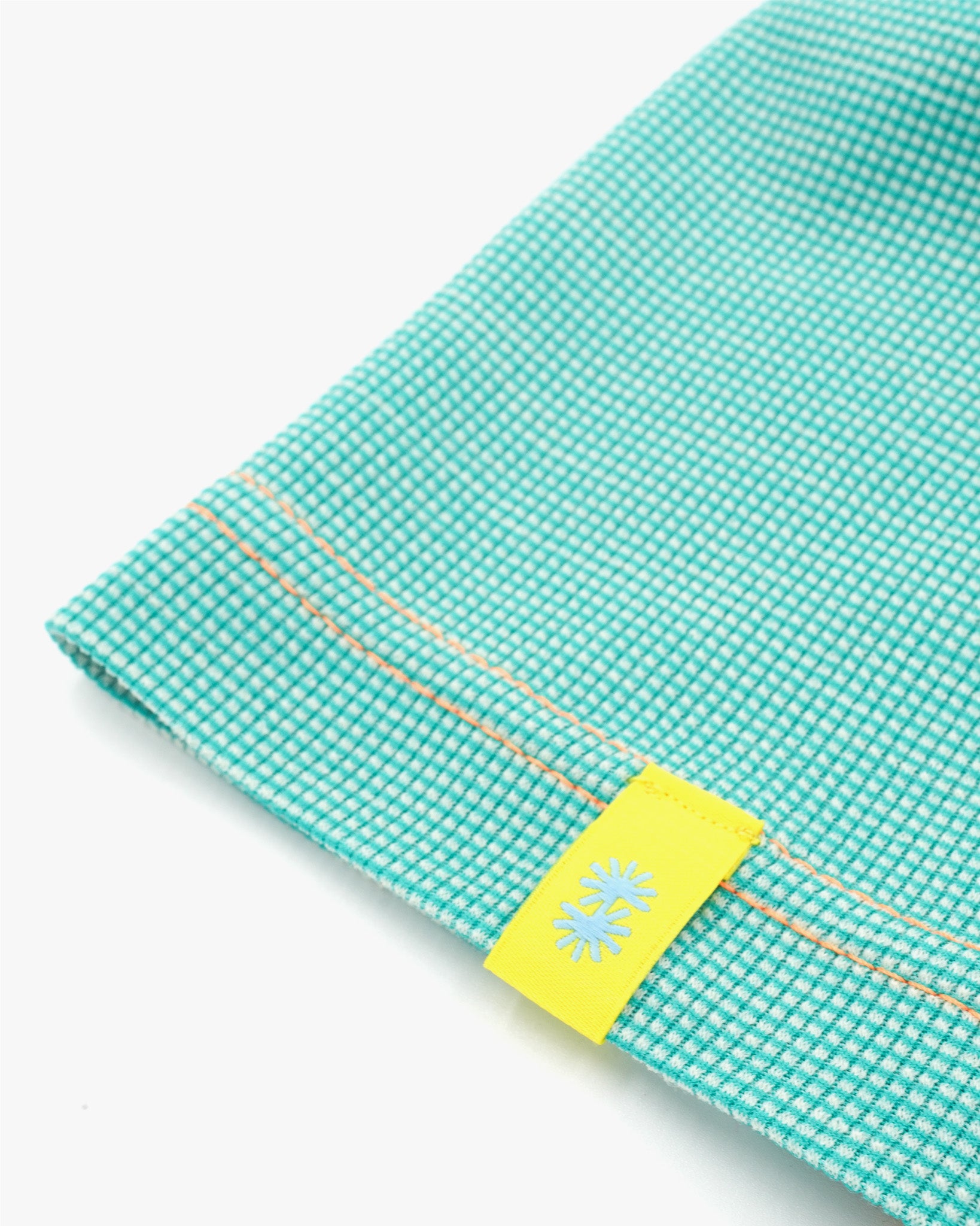 Close-up view of a long aqua blue Power Wool neck gaiter, with an orange back seam and yellow CTW logo woven label