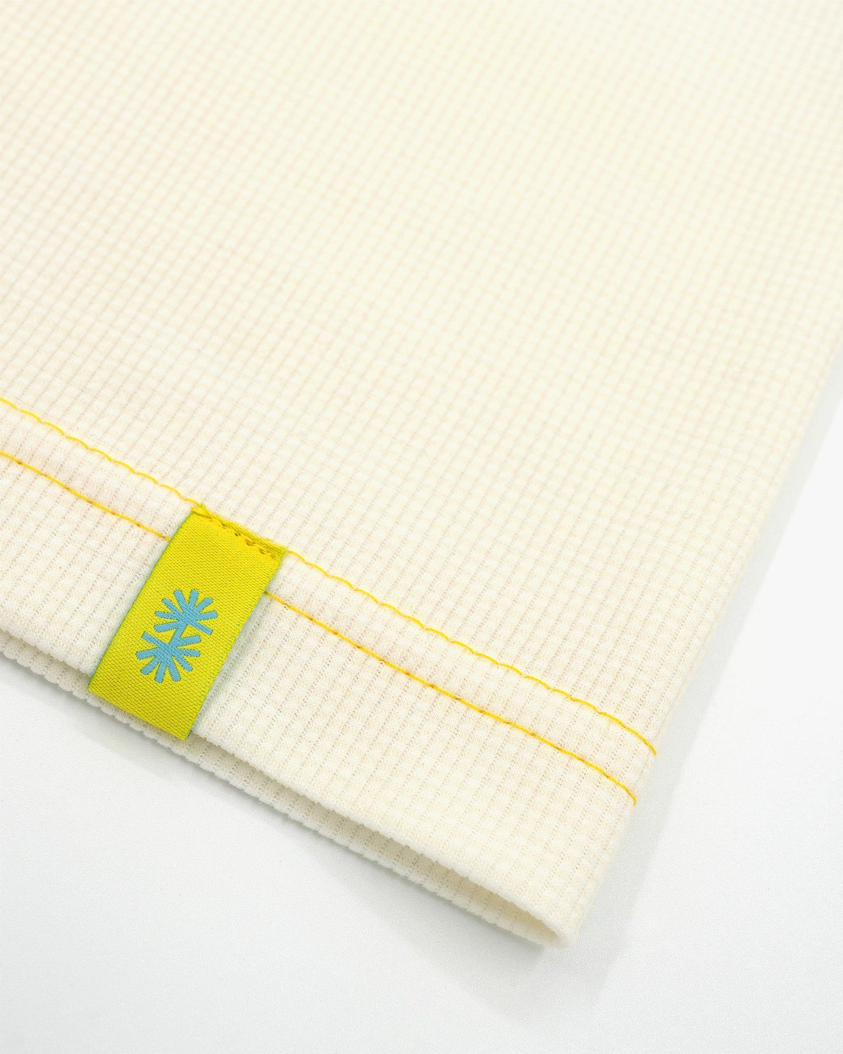 Close-up view of a long off-white Power Wool neck gaiter, with a yellow back seam and yellow CTW logo woven label