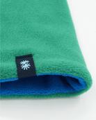 Close-up view of a polartec fleece blue front and green back reversible neck warmer, with a black CTW logo woven label